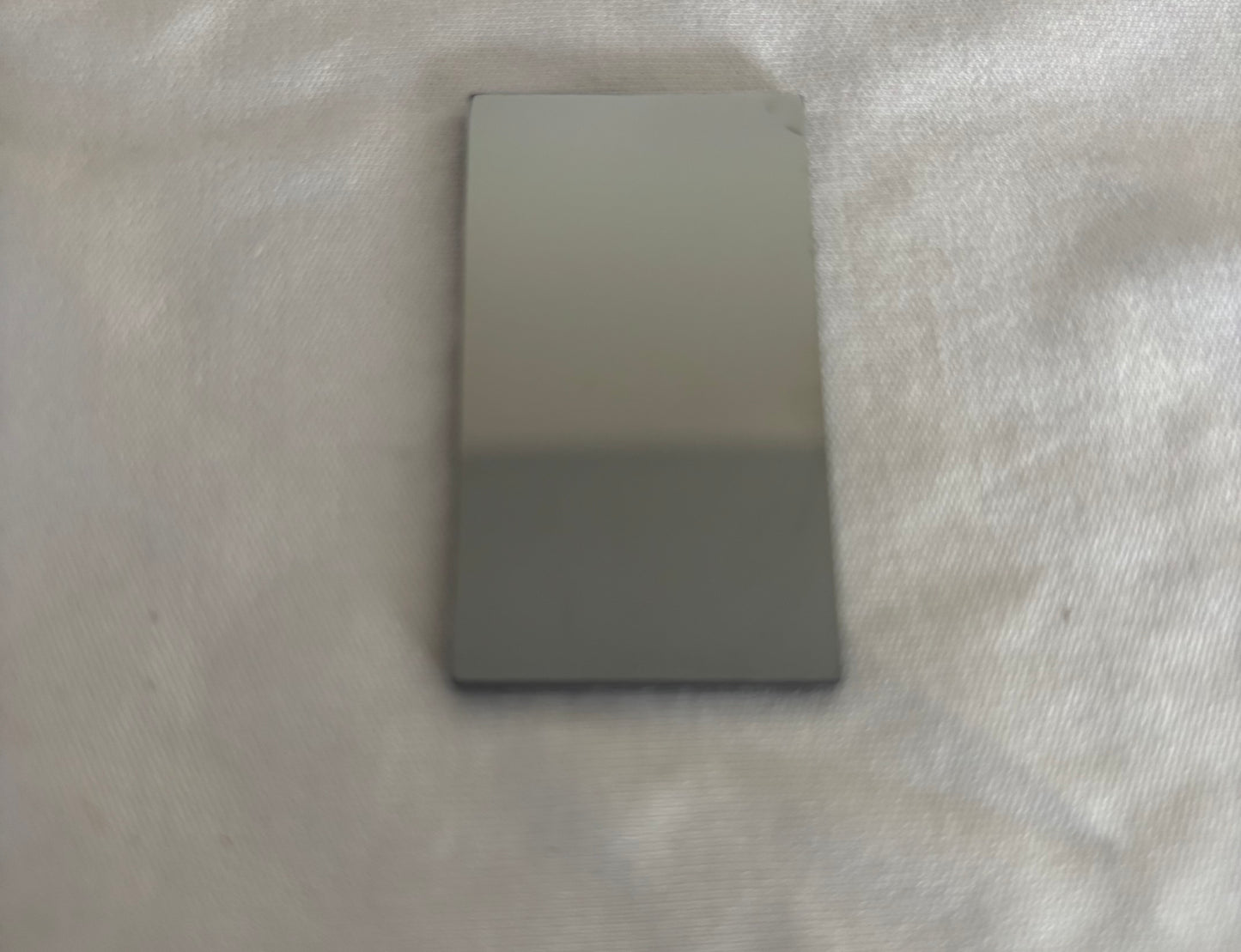 Rectangular glossy gray ceramic tile on textured fabric surface