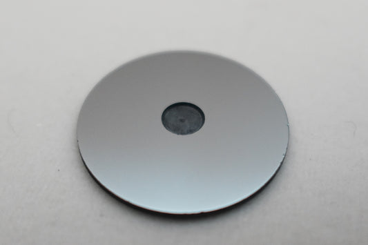 round metallic sample holder with central indentation on white background
